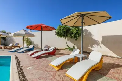 a group of chairs and umbrellas next to a pool at La bonita compound in Hurghada