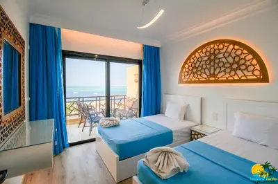 a bedroom with two beds and a balcony with the ocean at Bellevue The View in Hurghada