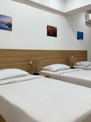 three beds in a room with white sheets at Lilly Stays Sheraton Road in Hurghada