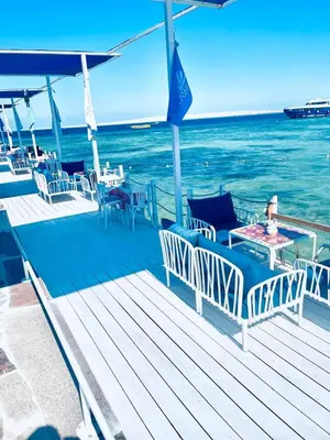 a deck with chairs and tables on the water at Lilly Stays Sheraton Road in Hurghada