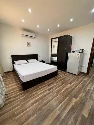 a bedroom with a white bed and a refrigerator at Lilly Stays Sheraton Road in Hurghada