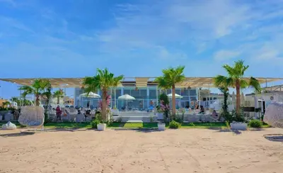 a resort on the beach with palm trees and chairs at Selina Apartments in Hurghada