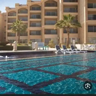 a swimming pool with chairs in front of a building at Selina Apartments in Hurghada