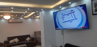 a television on a wall in a room with a couch at Aswan Nile view palace in Naj‘ al ‘Amrāb