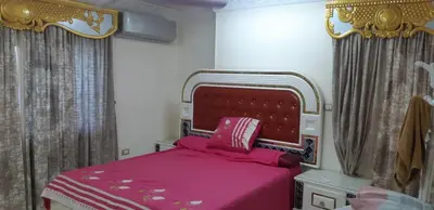 a bedroom with a bed with a pink bedspread and curtains at Aswan Nile view palace in Naj‘ al ‘Amrāb