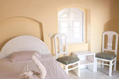 a bedroom with a white bed with two chairs at Luxor Nile View Flats in Luxor