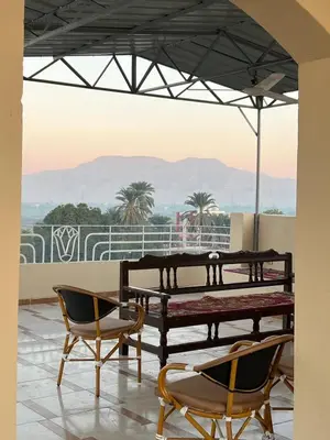 a patio with a table and chairs and a view of mountains at Luxor Nile View Flats in Luxor