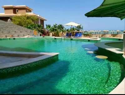 a swimming pool with blue water and an umbrella at Apartment - Sleeps 4 - Pool - Pet friendly in Hurghada