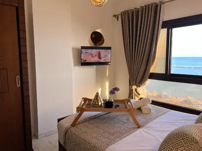 a bedroom with a bed with a table and a window at Apartment - Sleeps 4 - Pool - Pet friendly in Hurghada