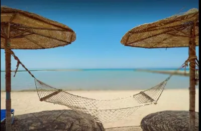 a hammock on a beach with umbrellas and the ocean at Apartment - Sleeps 4 - Pool - Pet friendly in Hurghada