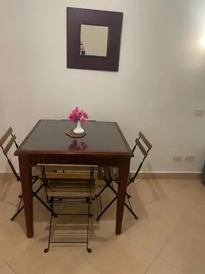 a wooden table with two chairs and a vase with flowers on it at Sunset pearl sahl hasheesh in Hurghada