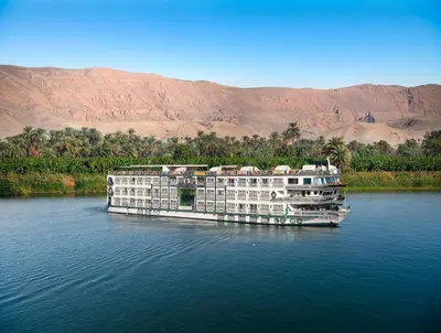 a large boat on the water with mountains in the background at Sonesta St George Nile Cruise - Luxor to Aswan 4 Nights from Monday to Friday in Luxor