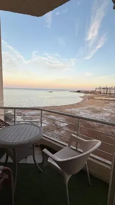 a balcony with a table and a chair and the beach at Casablanca Beach Direct sea view Tow Bedroom Apartment in Hurghada