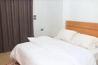 a bed with white sheets and pillows in a bedroom at Royal Mountain in Luxor