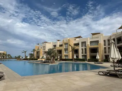 a swimming pool in front of a large building at Mangroovy Tasteful 1 bedroom in Hurghada