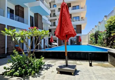 a red umbrella in front of a swimming pool at 3BR 2BA Retreat with Four Pools Gym and Onsite Dining Close to El Gouna in Hurghada