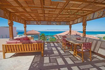 a patio with a wooden pergola and a table and chairs at Soma Bay Seafront Luxury Appartement in Hurghada