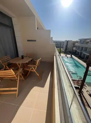 a balcony with a table and chairs and a swimming pool at Brand new studio at G-Cribs ElGouna in Hurghada