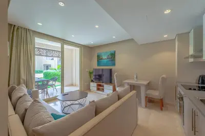 a living room with a large couch and a kitchen at Cozy 1-Bedroom Apartment in Mangroovy, El Gouna. Private terrace, garden and pool access in Hurghada