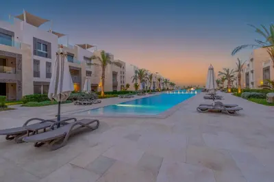 a resort swimming pool with umbrellas and chairs at Cozy 1-Bedroom Apartment in Mangroovy, El Gouna. Private terrace, garden and pool access in Hurghada