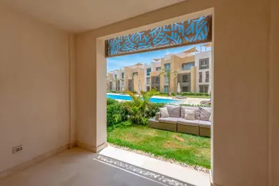 an open door into a living room with a view of a pool at Cozy 1-Bedroom Apartment in Mangroovy, El Gouna. Private terrace, garden and pool access in Hurghada