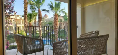 two chairs sitting on a balcony with palm trees at veranda sahl hasheesh resort in Hurghada