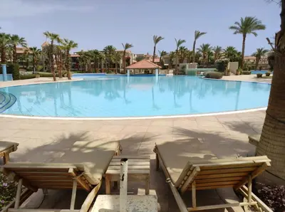 a large swimming pool with two chairs in front of it at veranda sahl hasheesh resort studio in Hurghada