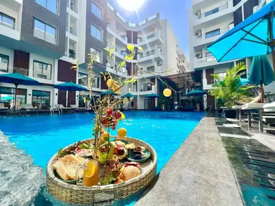 a resort pool with a table with food and a plant at 2 Bed Resort Apt-Sleeps 4-Balcony-Hotel Services in Hurghada