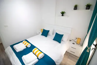 a bedroom with a white bed with blue and yellow pillows at 2 Bed Resort Apt-Sleeps 4-Balcony-Hotel Services in Hurghada