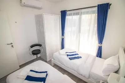 a bedroom with a bed and a window with blue curtains at 2 Bed Resort Apartment - Sleeps 4 - Hotel Services in Hurghada