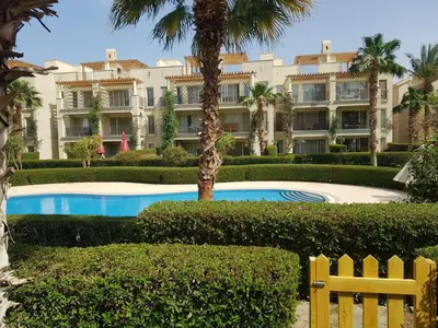 a resort with a swimming pool in front of a building at شقه غرفتين وصاله بالحديقه في فراندا سهل حشيش in Hurghada