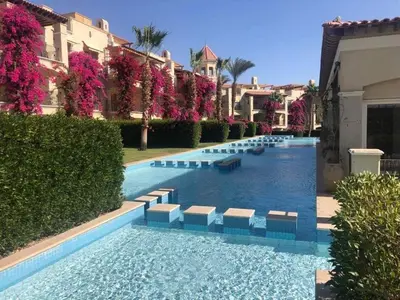 a swimming pool with benches in a resort at شقه غرفتين وصاله بالحديقه في فراندا سهل حشيش in Hurghada