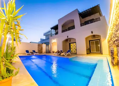 a villa with a swimming pool in front of a house at Royal Home Luxor Pool View in Luxor