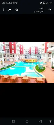 a large swimming pool with tables and chairs in a building at One bedroom apartment in Aqua palm resort before Al Gouna in Hurghada