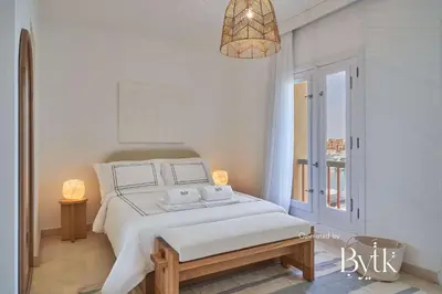 a white bedroom with a bed and a pendant light at BYTK - La Veranda in Hurghada