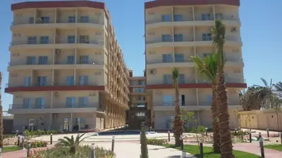 a large building with palm trees in front of it at Chalet in Casablanca Beach Resort in Hurghada