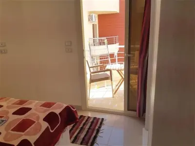 a room with a bed and a balcony with a chair at Chalet in Casablanca Beach Resort in Hurghada