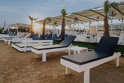 a group of lounge chairs on a beach with palm trees at Amazing 2 bedroom Selena Bay Hurghada in Hurghada