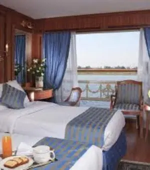 a hotel room with a bed and a table with food at Nile Cruise Aswan & Luxor & Abu Simbel in Luxor