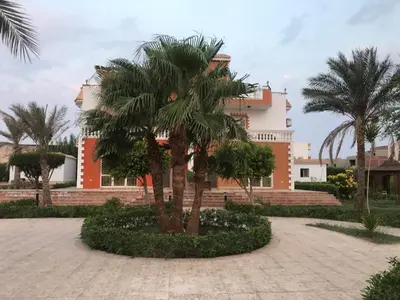 a building with palm trees in front of it at Moubark 6 Directly to the swimming pool in Hurghada