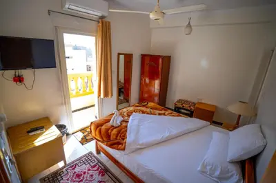 a bedroom with two beds and a television and a balcony at Venus Hotel Luxor \u65e5\u672c\u4eba \u5927\u6b53\u8fce in Luxor