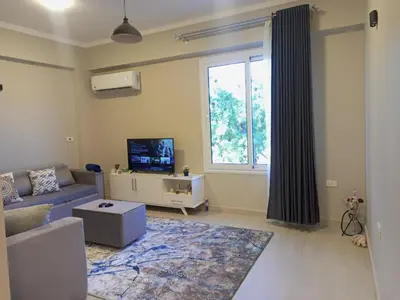 a living room with a couch and a tv and a window at WestLuxApartment in Al Karnak