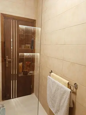 a shower with a glass door and a towel at WestLuxApartment in Al Karnak