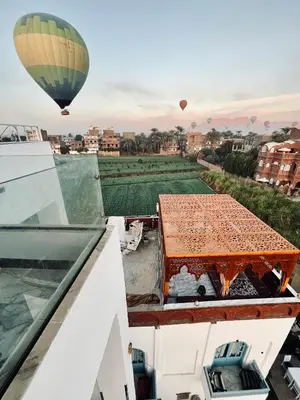 a hot air balloon flying over a building with a table at Flower Of Life Hotel in Luxor