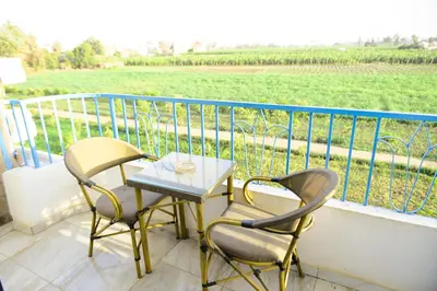 a table and two chairs on a balcony with a field at Flamingo Boutique hotels in Luxor