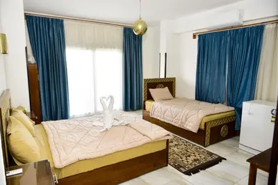 a bedroom with two beds and blue curtains at Flamingo Boutique hotels in Luxor