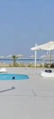 a swimming pool with an umbrella and the ocean at Scandic Cinde in Hurghada