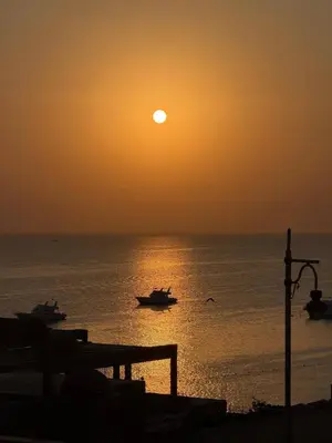a sunset over the ocean with boats in the water at BLUE ViEW SUiTES in Hurghada