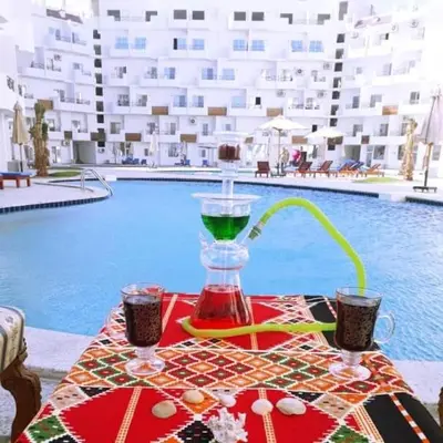 a table with a drink on a table next to a pool at منتجع طيبة فيو Tiba view in Hurghada