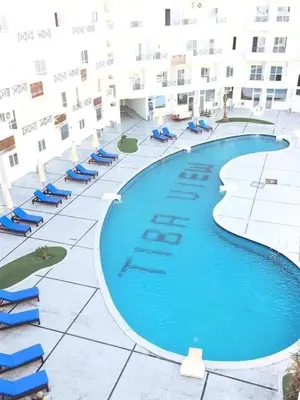 a large swimming pool with blue chairs and a building at منتجع طيبة فيو Tiba view in Hurghada